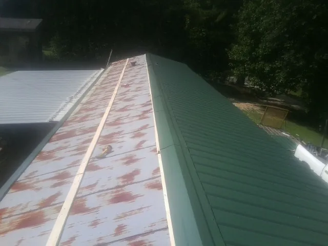 Old rusted panels beside newly installed green metal roofing — Wind Damage Roof Repair by Roofing Brothers in Wheelwright