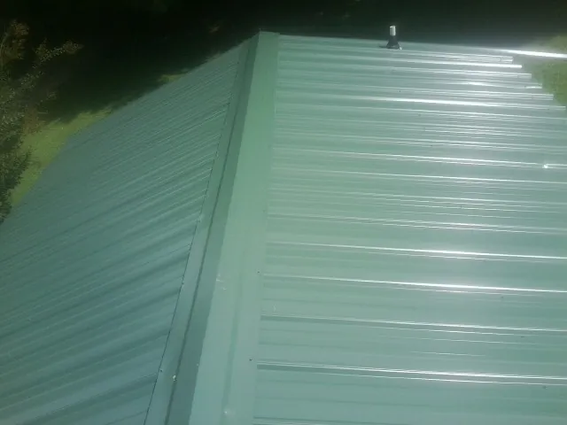 New green metal panels meeting at the ridge of a roof — Flat Roof Repair work by our crew in Wheelwright