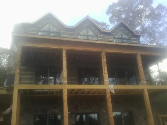 Dormers and porch framing on a large log home under construction — Roof Coating work by our crew in Wheelwright