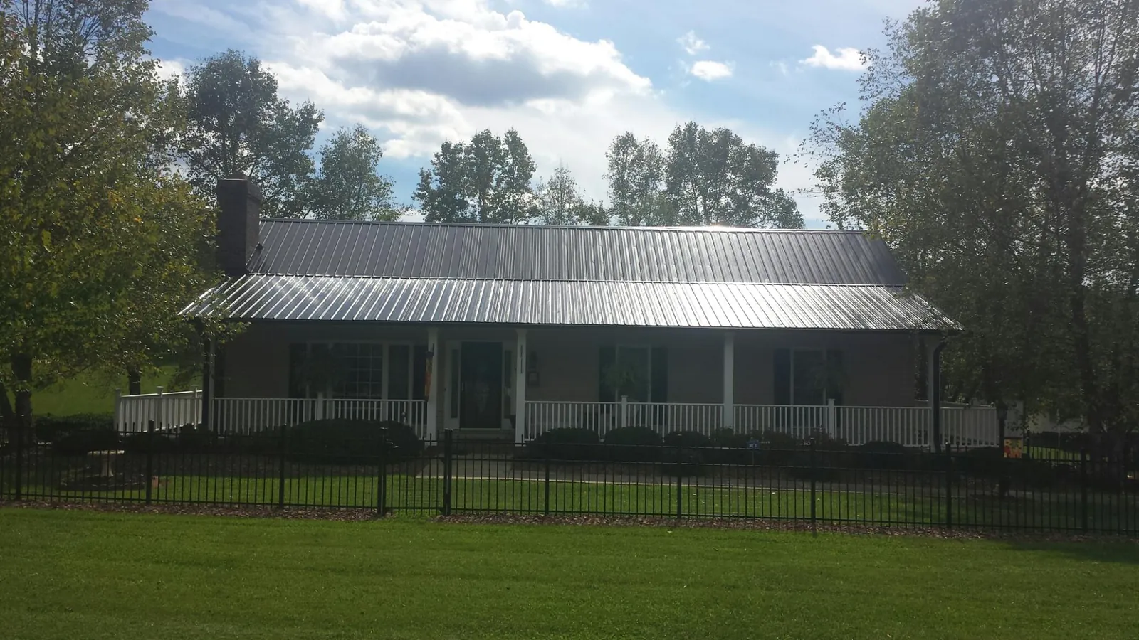 Gray metal roof on a brick ranch with a full width front porch — Gutter Guard Installation work by our crew in Wheelwright