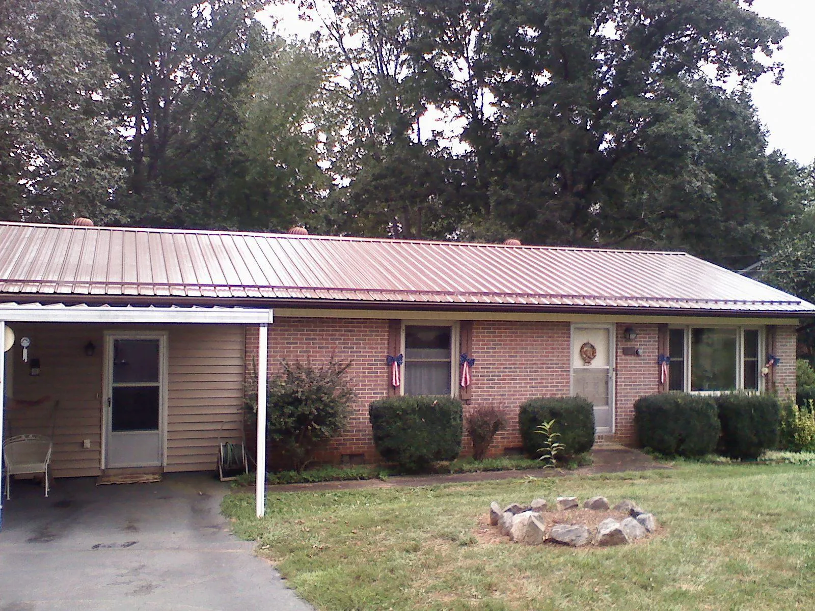 Bronze metal roof and carport on a brick ranch home — Roof Repair work by our crew in Wheelwright